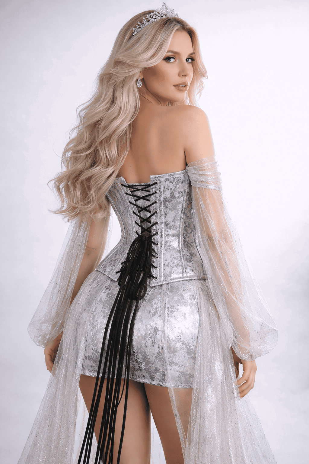 Woman wearing a silver sequin corset dress with long sleeves and a tiara on a white background